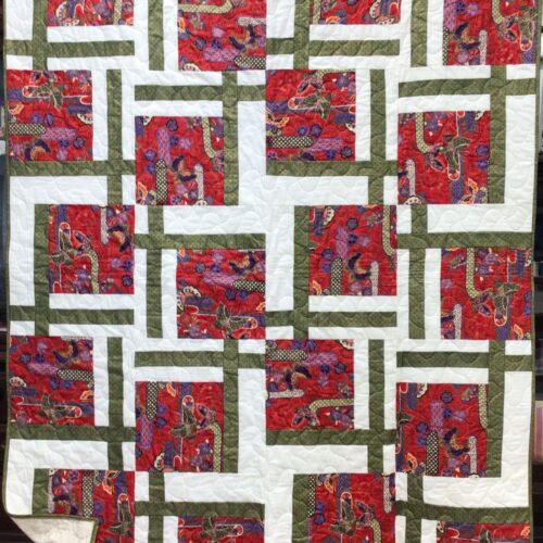 Lap quilt with Asian-themed red butterfly and floral print blocks framed by white and olive green strips