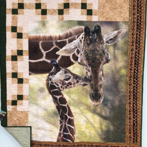 Lap quilt featuring mother and baby giraffe panel with pieced blocks and African-inspired geometric borders