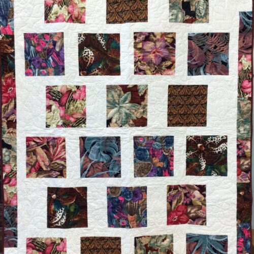 Modern Bold Florals quilt with large botanical squares set on a white background with a scrappy border and long-arm flower quilting.