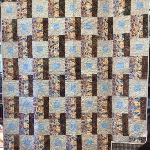 Throw quilt with alternating square-in-a-square blocks and batik strip blocks in browns, golds, and blues