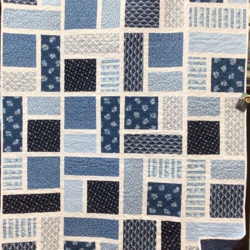 Modern Day at the Spa quilt featuring staggered blue rectangles and squares set in crisp white sashing