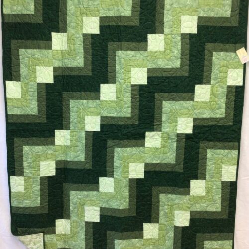 Throw quilt with quarter log cabin blocks in shades of green from forest to light green with loopy quilting