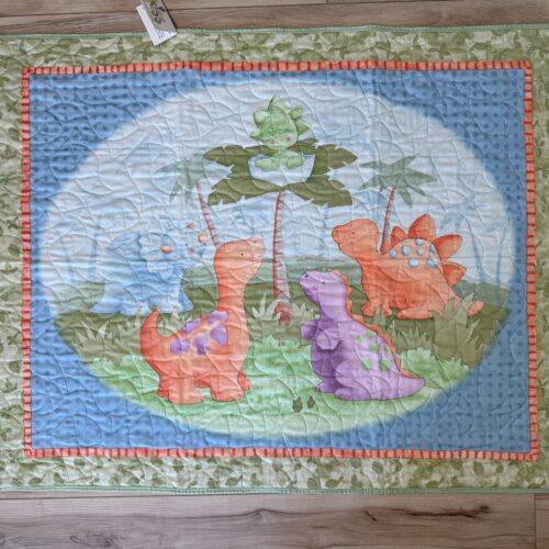 Baby Dinosaur panel quilt featuring a newly-hatched dinosaur in a tree surrounded by prehistoric friends.