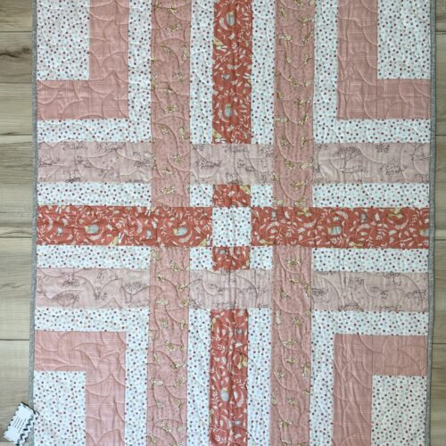 Handmade baby quilt based on Cluck Cluck Sew pattern Woven in peach and coral tones, featuring bunny and hedgehog prints with gray binding.