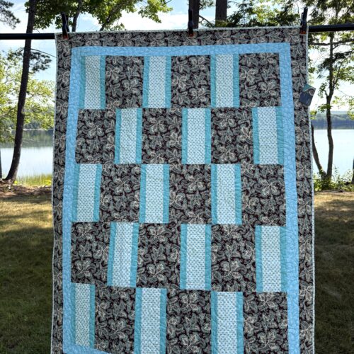 Lap quilt with offset brick pattern featuring brown paisley rectangles alternating with polka dot rectangles, teal sashing, and paisley border