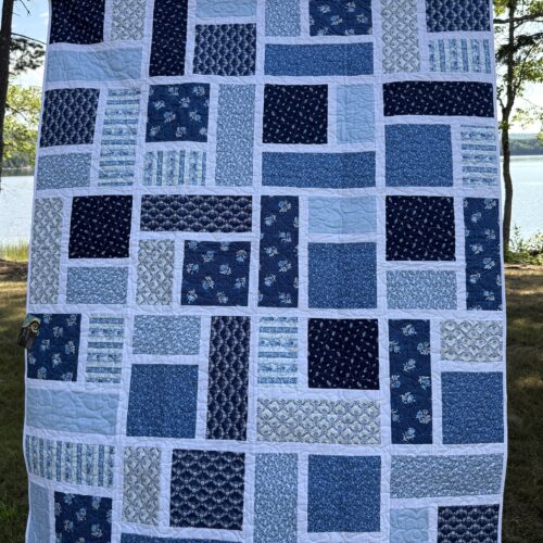 Modern Day at the Spa quilt featuring staggered blue rectangles and squares set in crisp white sashing