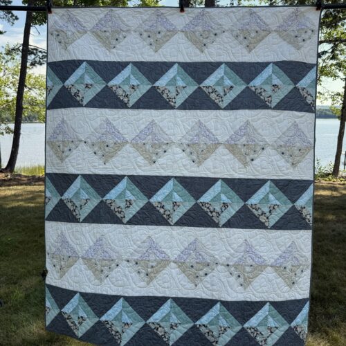 Bed-size quilt with Night and Day blocks set on point creating diamond rows in charcoal gray with teal and cream with neutrals