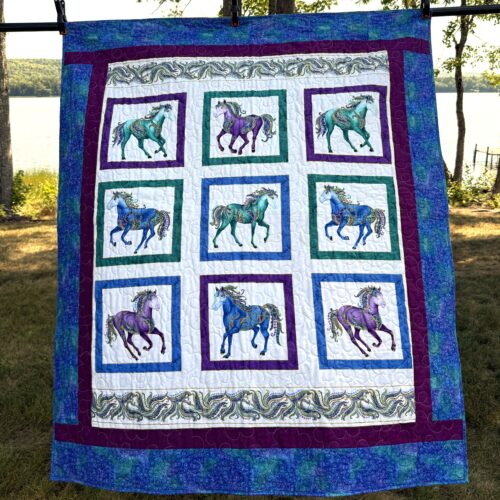 Panel quilt featuring nine carousel horses in jewel tones of teal, purple, and blue with ornate decorations, framed with multiple borders