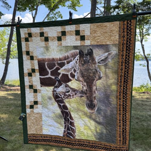 Lap quilt featuring mother and baby giraffe panel with pieced blocks and African-inspired geometric borders