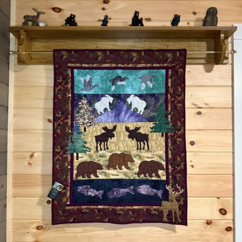 Wildlife wall hanging featuring four scenic panels with waterfowl, mountain goats, moose, bears, and fish in raw edge appliqué with burgundy oak leaf border