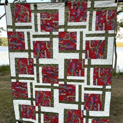 Lap quilt with Asian-themed red butterfly and floral print blocks framed by white and olive green strips