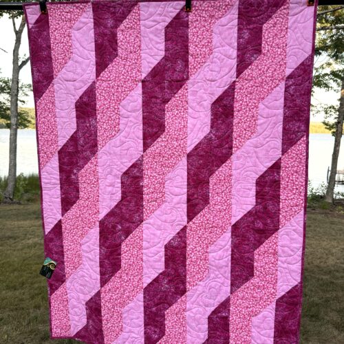 Lap quilt with diagonal ribbon braid pattern in pinks and magenta creating woven effect