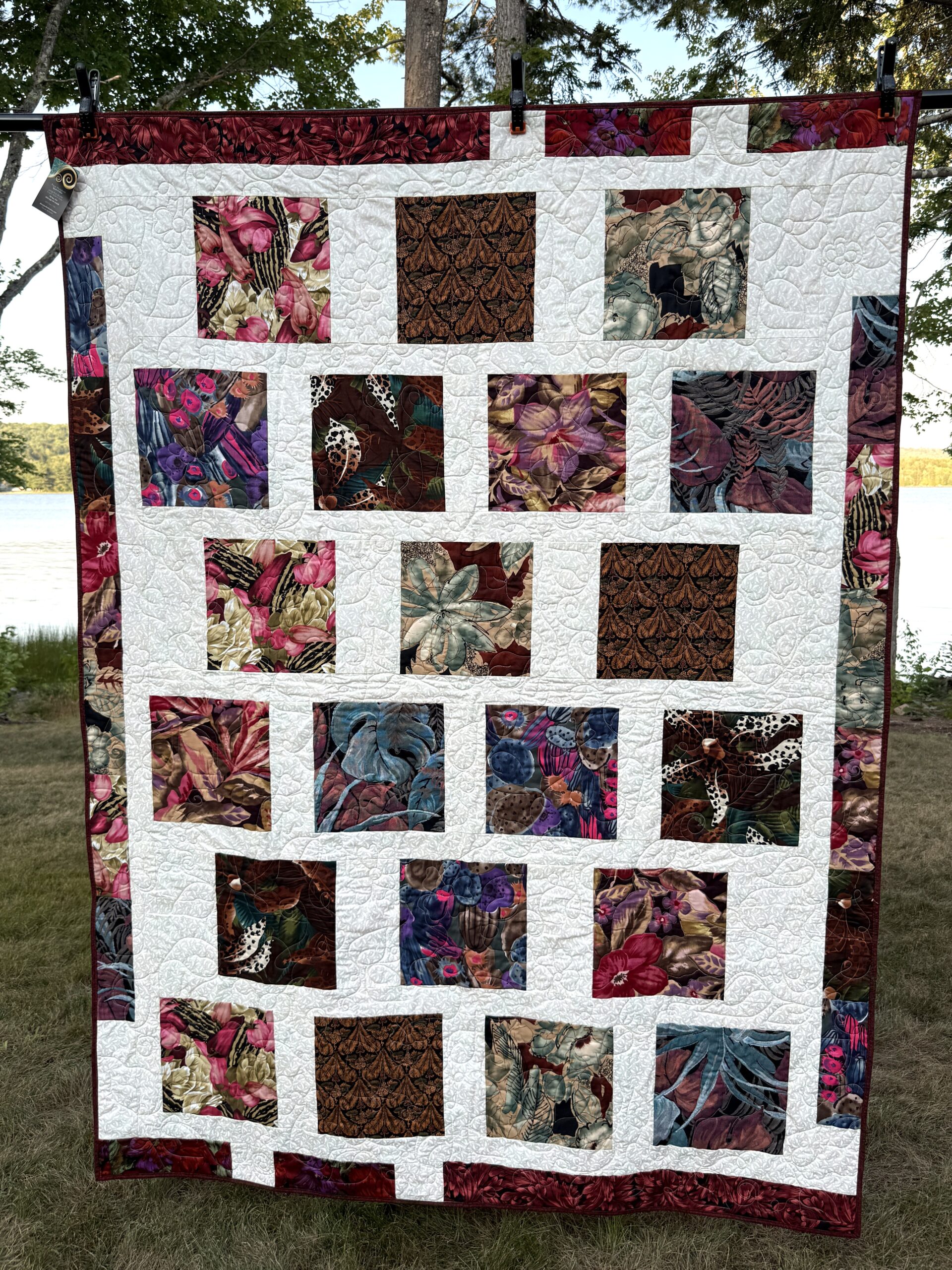 Modern Bold Florals quilt with large botanical squares set on a white background with a scrappy border and long-arm flower quilting.