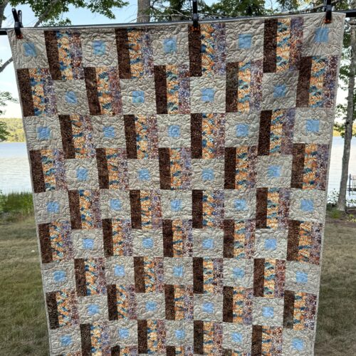 Throw quilt with alternating square-in-a-square blocks and batik strip blocks in browns, golds, and blues