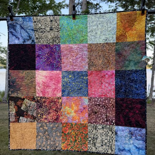 Square lap quilt featuring 25 large batik fabric squares in vibrant colors including blues, purples, pinks, oranges, and greens