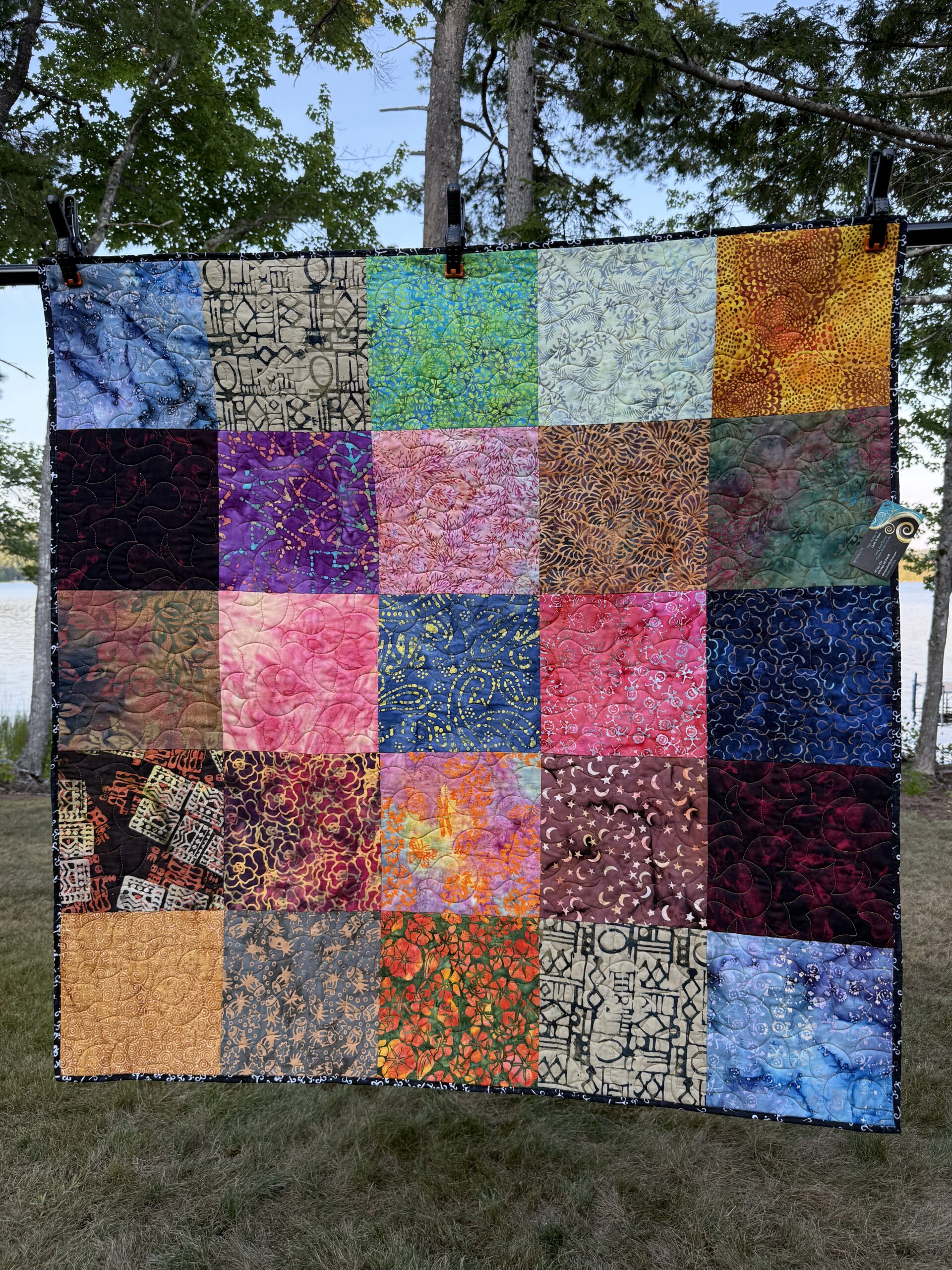 Square lap quilt featuring 25 large batik fabric squares in vibrant colors including blues, purples, pinks, oranges, and greens