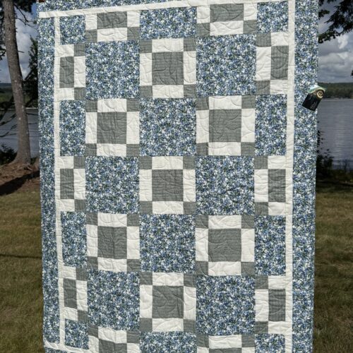 Throw quilt with blueberry print squares alternating with uneven nine-patch blocks in soft green and off white