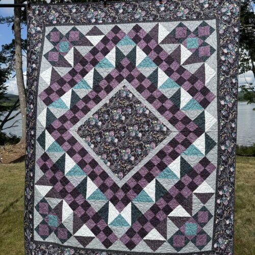 Based on midnight romance from needle in a hayes stack, this medallion quilt has a dark floral center diamond surrounded by purple, teal, gray blocks of various types, and matching floral border
