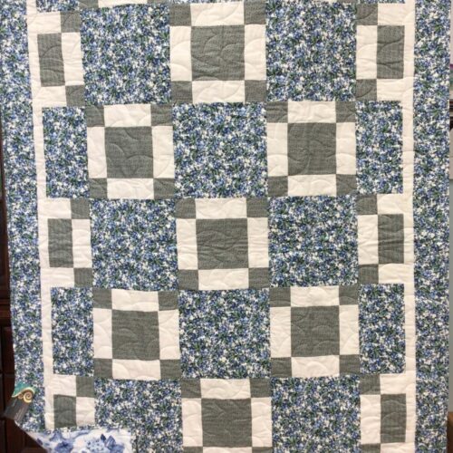 Throw quilt with blueberry print squares alternating with uneven nine-patch blocks in soft green and off white