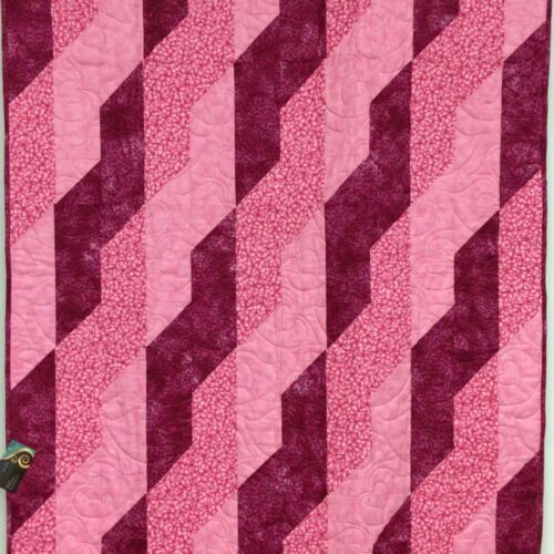 Lap quilt with diagonal ribbon braid pattern in pinks and magenta creating woven effect