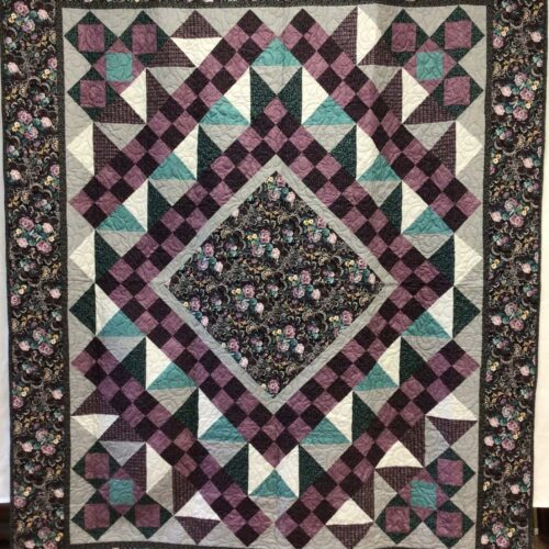 Based on midnight romance from needle in a hayes stack, this medallion quilt has a dark floral center diamond surrounded by purple, teal, gray blocks of various types, and matching floral border