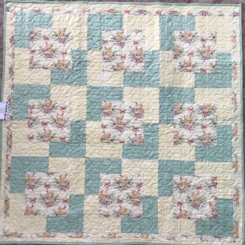 Handmade baby quilt with fawn and floral print blocks framed in soft mint green and pale yellow, pieced in the Town Square pattern from Fabric Cafe
