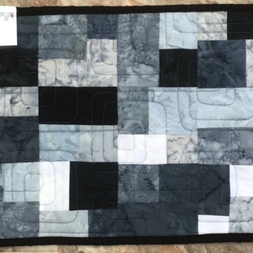 Modern quilted table runner with blocks in gray, black, and white fabrics with Bauhaus geometric quilting