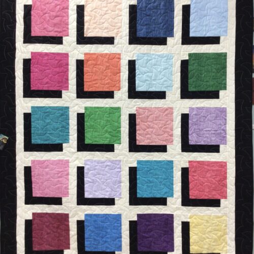 Throw quilt with shadow box pattern creating 3D illusion using colored squares with black shadows on white background and black border