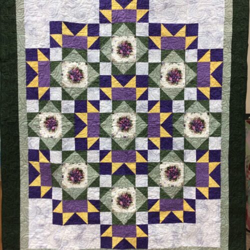 Throw quilt with circle of nine pansy bouquets in green, purple, and yellow