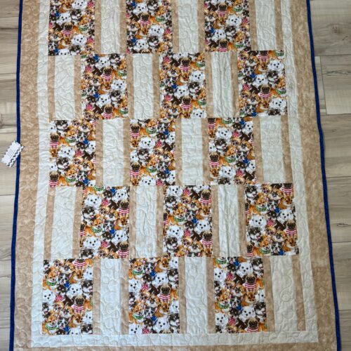 Handmade baby quilt with packed puppy print blocks in tan strip piecing, featuring playful dogs in costumes