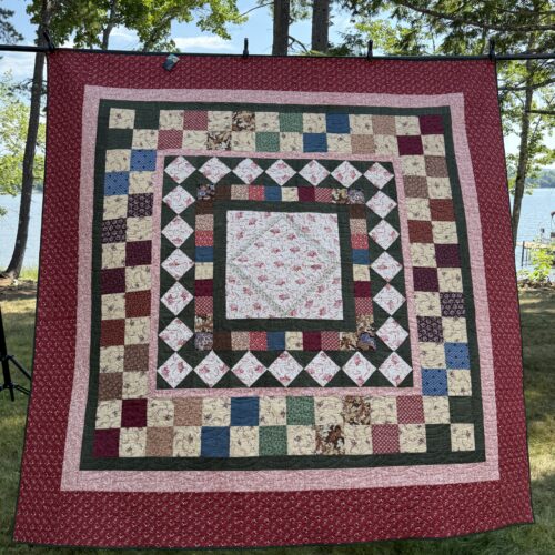 Full bed medallion quilt with floral center surrounded by diamond border, checkerboard, and multiple frames in burgundy, green, and pink