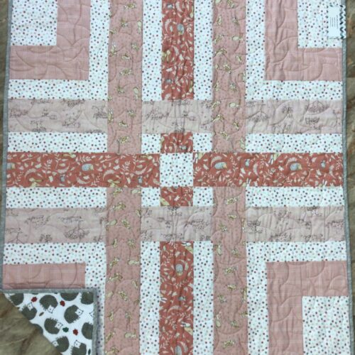 Handmade baby quilt based on Cluck Cluck Sew pattern Woven in peach and coral tones, featuring bunny and hedgehog prints with gray binding.