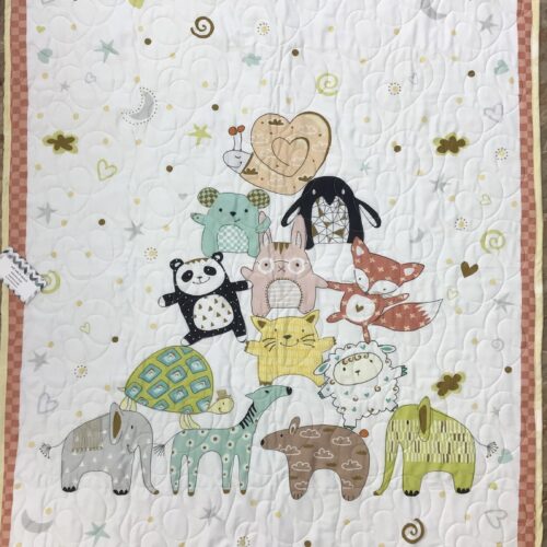 Handmade panel baby quilt with whimsical stacked animal characters including elephant, panda, fox, bunny, and turtle on a white background scattered with moons, stars, and hearts with a pink checkered border.