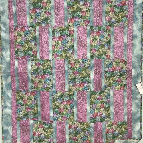 Handmade lap quilt with realistic succulent print blocks in green, teal, pink, and magenta, alternating with rose pink and pale teal strips, framed by a pink inner border and wide teal outer border.